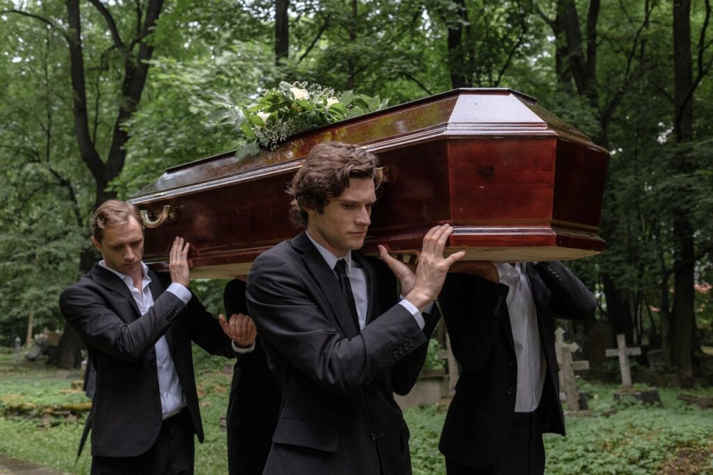 guys carrying funeral casket wearing a black suit
